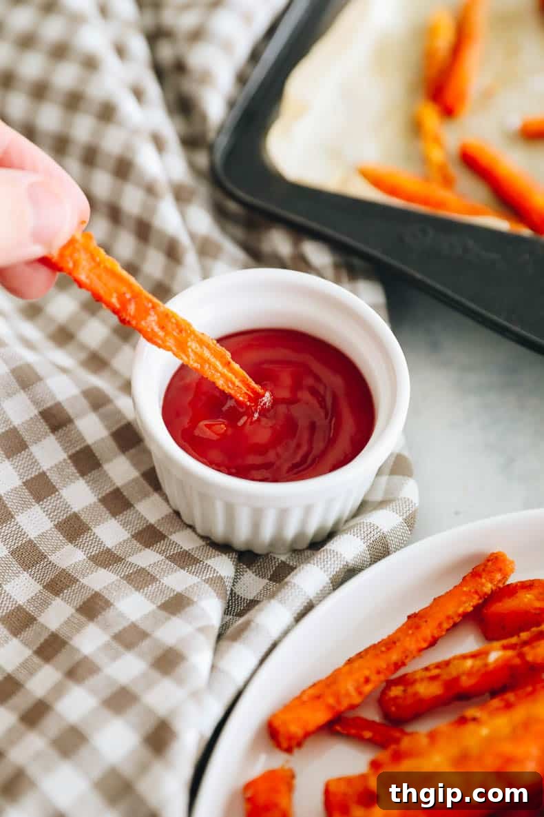 Golden Oven-Baked Carrot Sticks 7 crispy carrot fry being dipped into ketchup, showcasing its perfect texture.