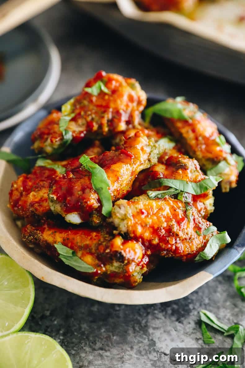 Baked thai chicken wings in a bowl topped with sprinkled thai basil.