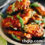 Baked thai chicken wings in a bowl with chopped thai basil.