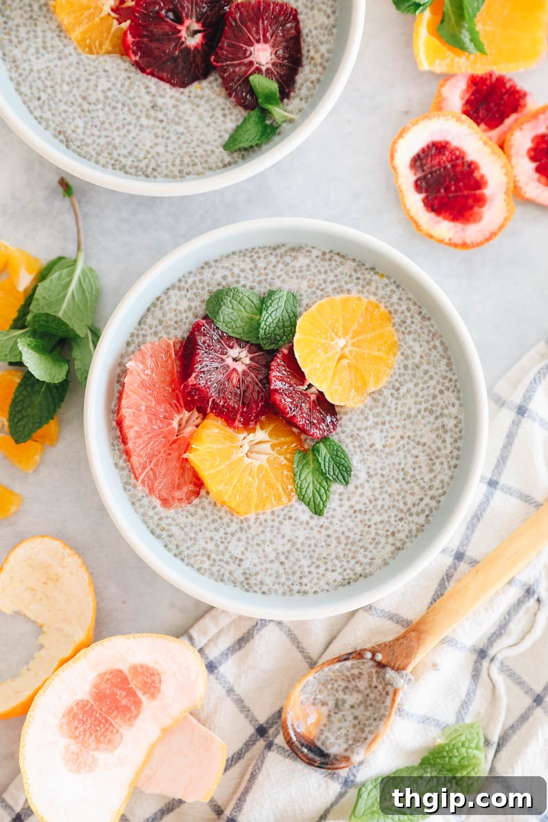 Sunshine Citrus Chia Pudding 7 Overhead shot of a blue and white bowl filled with creamy chia pudding, adorned with a colorful array of sliced grapefruit, blood orange, and tangelo, alongside a delicate mint leaf for garnish.