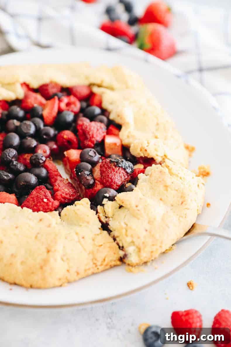 Berry Galette with Almond Flour Crust 2 A beautifully baked almond flour berry galette on a white plate, ready to be served, with a pie cutter nearby.
