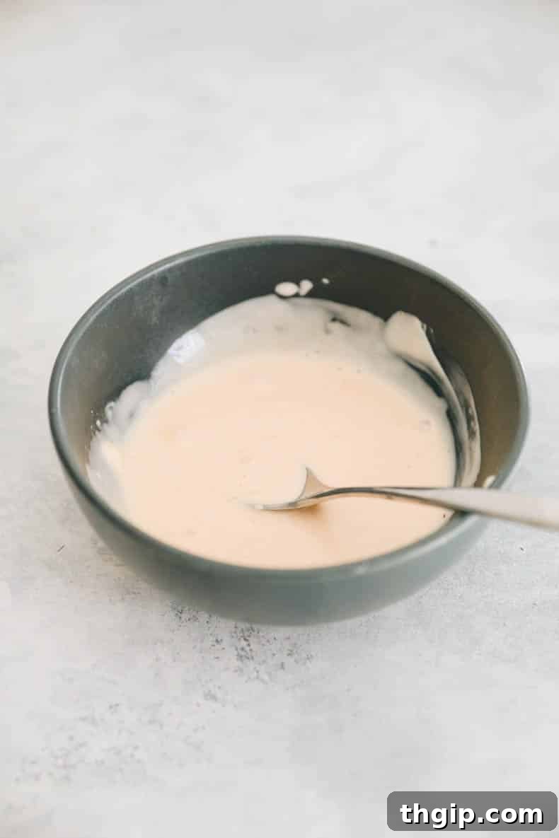 Creamy Spicy Crab Crunch 5 A creamy and spicy Kani Salad dressing, a blend of mayonnaise, sriracha, rice wine vinegar, and honey, prepared in a small blue bowl.