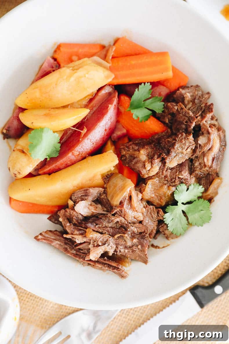 Close up of a savory chuck roast cooked in an Instant Pot, surrounded by vegetables.