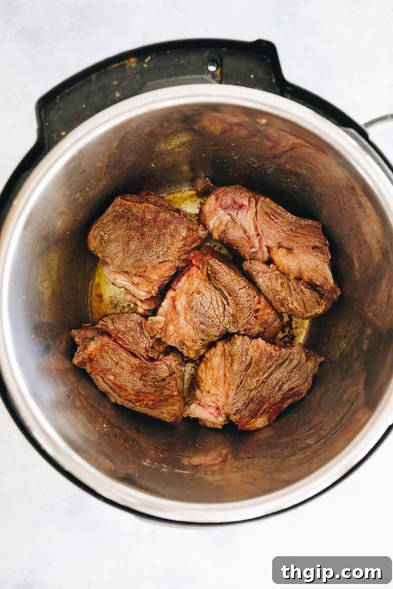 Seared chuck roast browning on all sides in an Instant Pot, a key step for deep flavor.