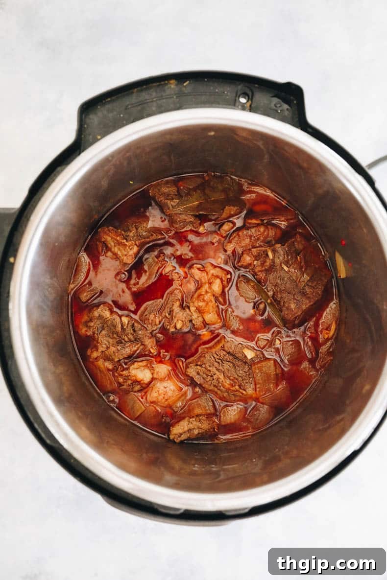 Chuck roast simmering in rich gravy within an Instant Pot, ready for pressure cooking.