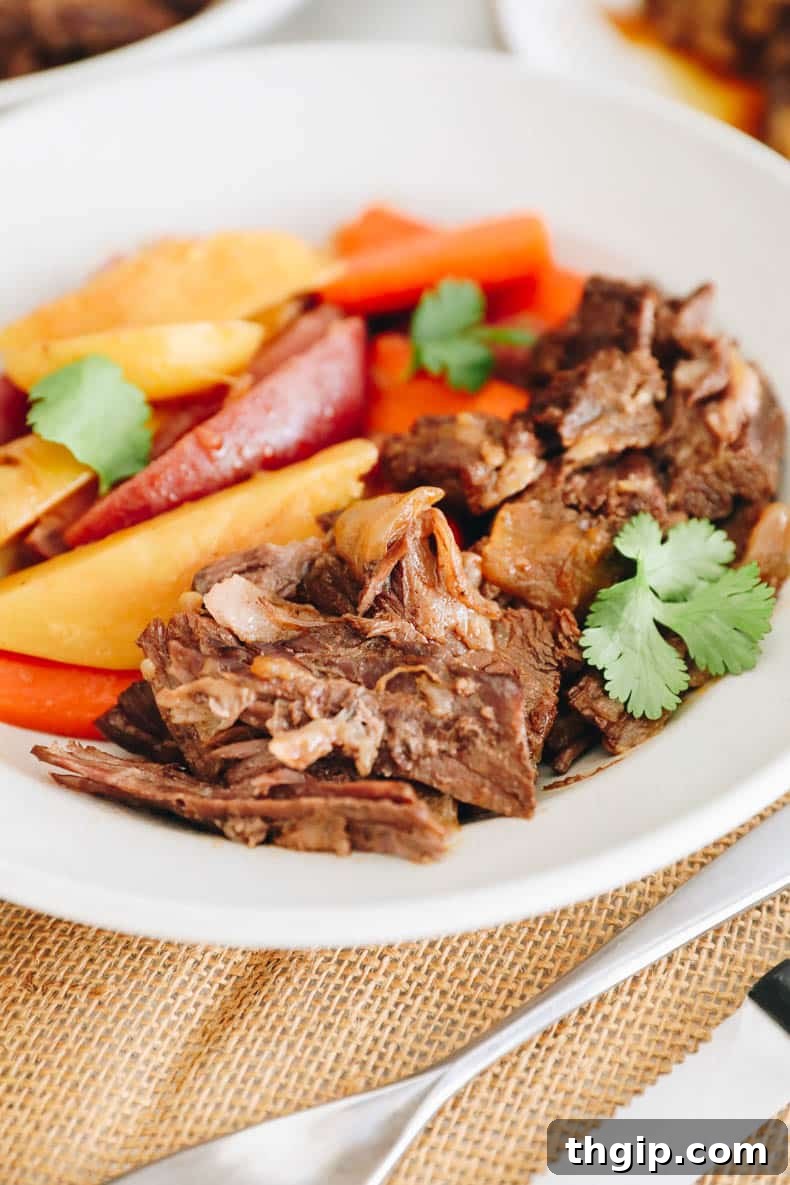 Instant Pot chuck roast with potatoes and carrots served in a white shallow bowl, drizzled with gravy.