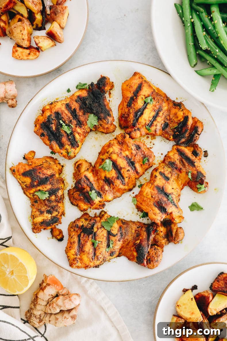 Grilled turmeric chicken on a white plate, garnished with fresh herbs.