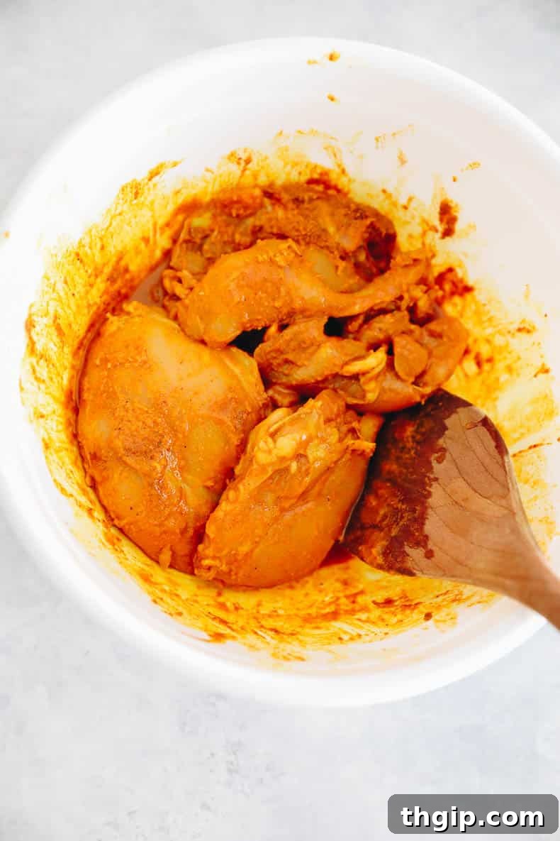 Chicken thighs soaking in a rich turmeric marinade.