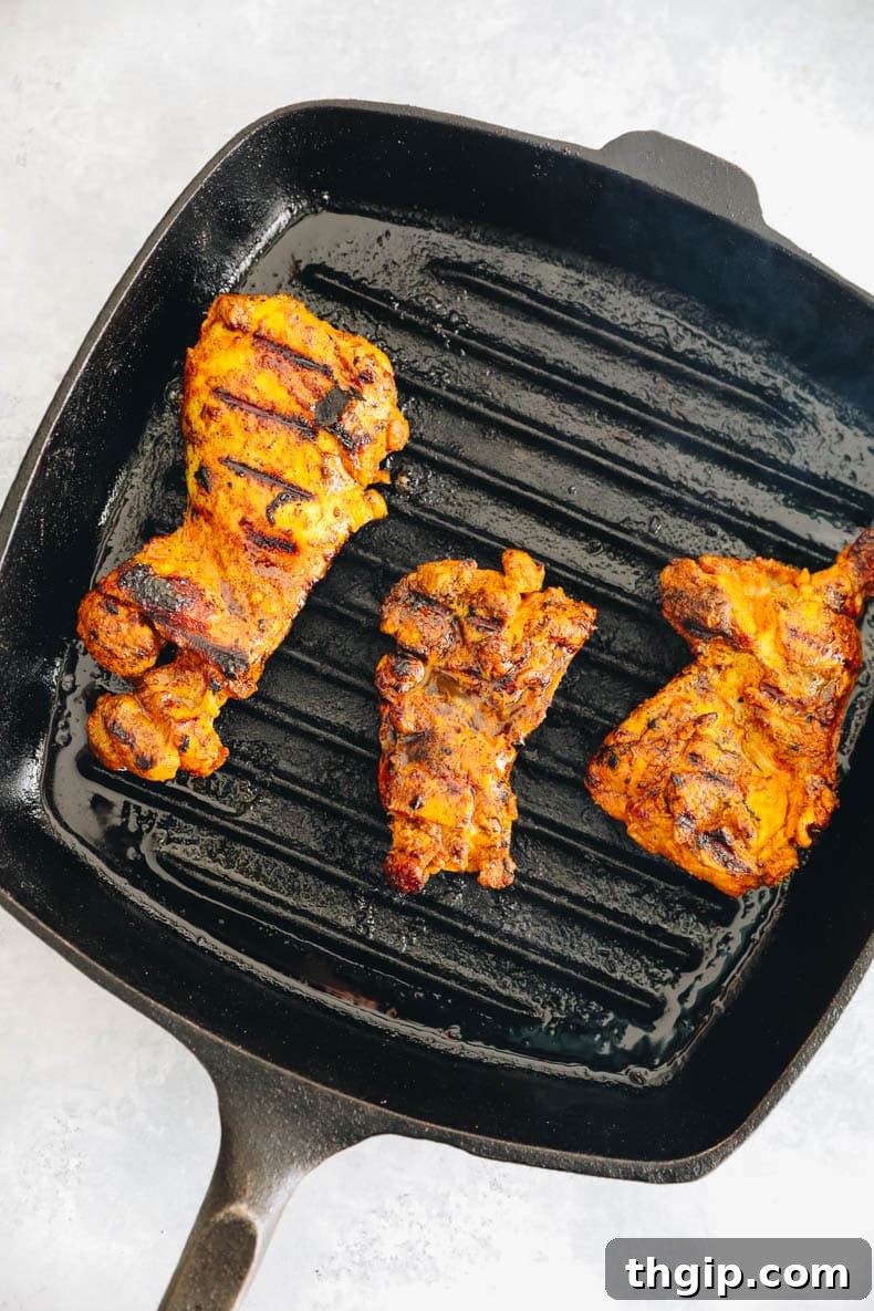 Grilled chicken thighs on a cast iron grill pan with perfect char marks.