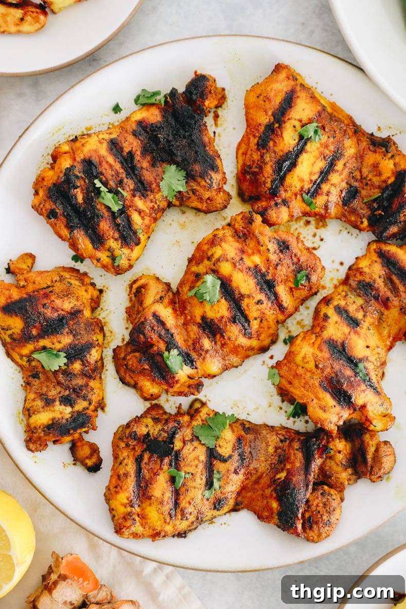 overhead of turmeric chicken thighs on a white plate, ready to be served.