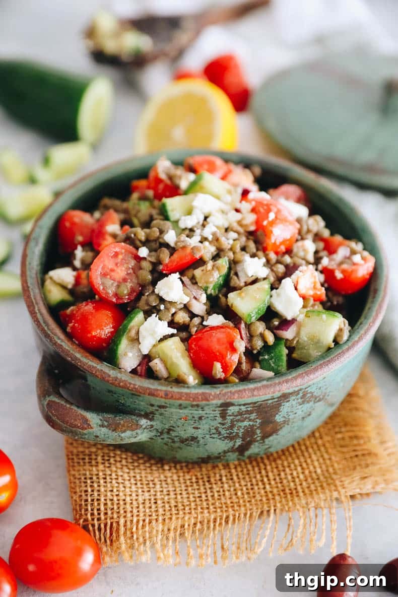 Vibrant Lentil Salad 2 Greek lentil salad with tomatoes, peppers, cucumbers, onions and feta in a green bowl.