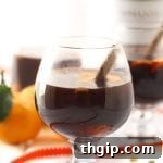 A close-up of Orange Chai Mulled Wine in a mug with orange slices and cinnamon sticks.