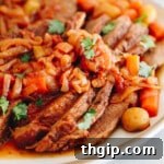 Classic Jewish brisket with caramelized onion, carrots, potatoes and parsley on a white platter.
