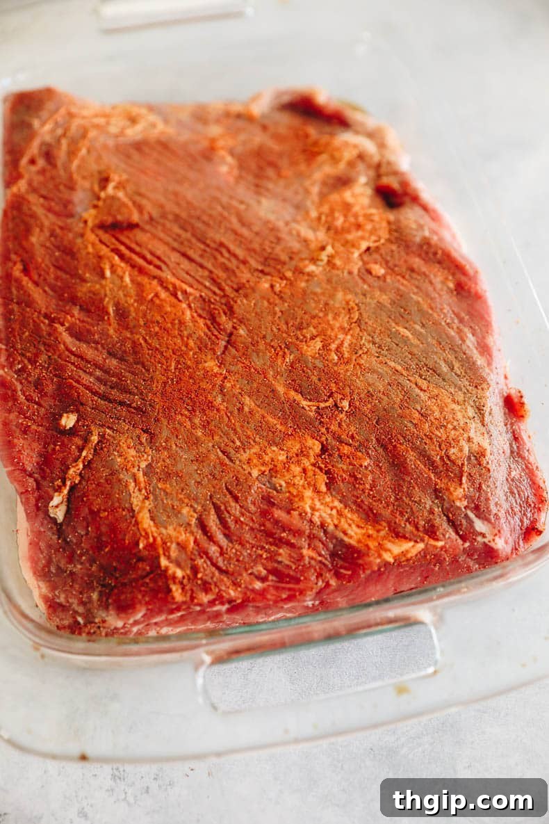 Perfectly Tender Smoked Brisket 3 Dry brined brisket, generously seasoned with kosher salt, black pepper, and paprika, resting in a baking dish, ready for cooking.