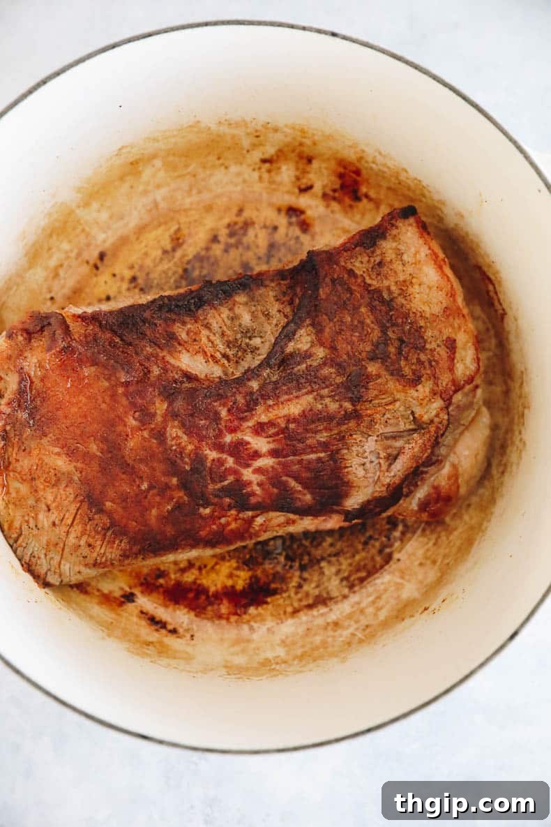 Perfectly Tender Smoked Brisket 4 A perfectly seared brisket, featuring a golden-brown crust, resting in a Dutch oven after initial browning.