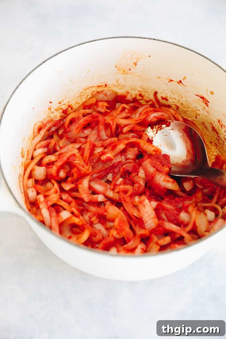 Perfectly Tender Smoked Brisket 6 Caramelized sweet onions mixed with rich tomato paste, creating a fragrant base for the brisket sauce in a Dutch oven.