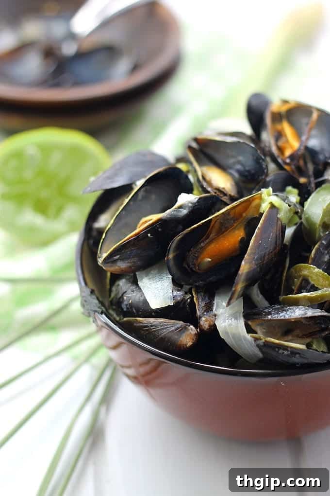 Fresh Thai Curry Mussels garnished with basil and lime, served with a spoon