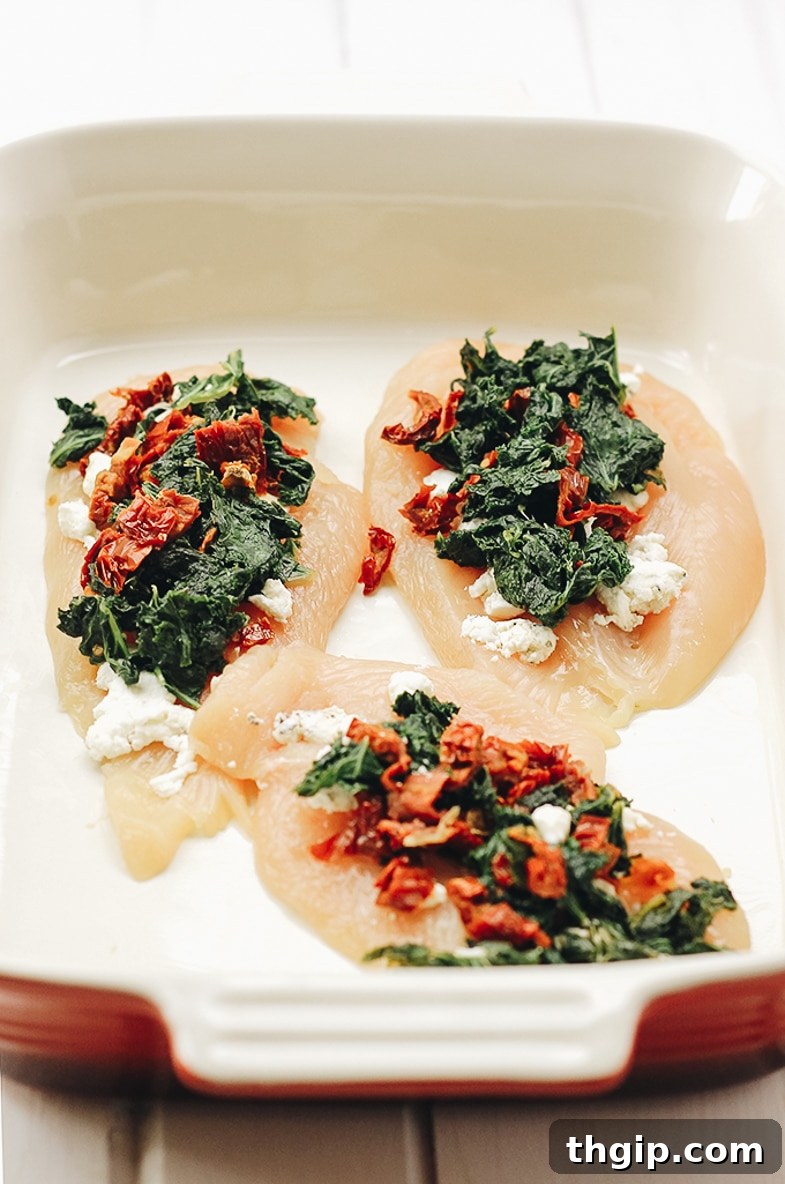 Rolled chicken breasts stuffed with kale, sundried tomatoes, and goat cheese in a baking dish.