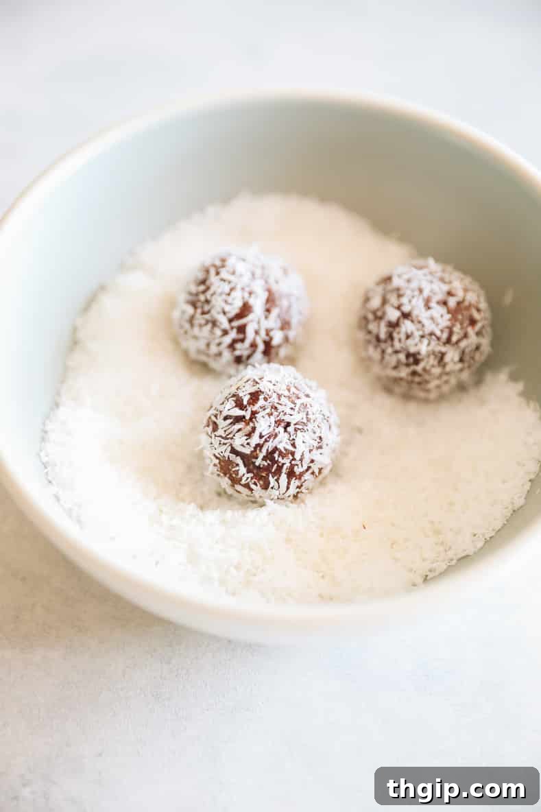 Coconut Almond Bliss Bites 5 Almond joy energy balls sitting in a bowl of shredded coconut.