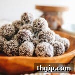 Close up shot of almond joy energy balls stacked on a wooden platter.