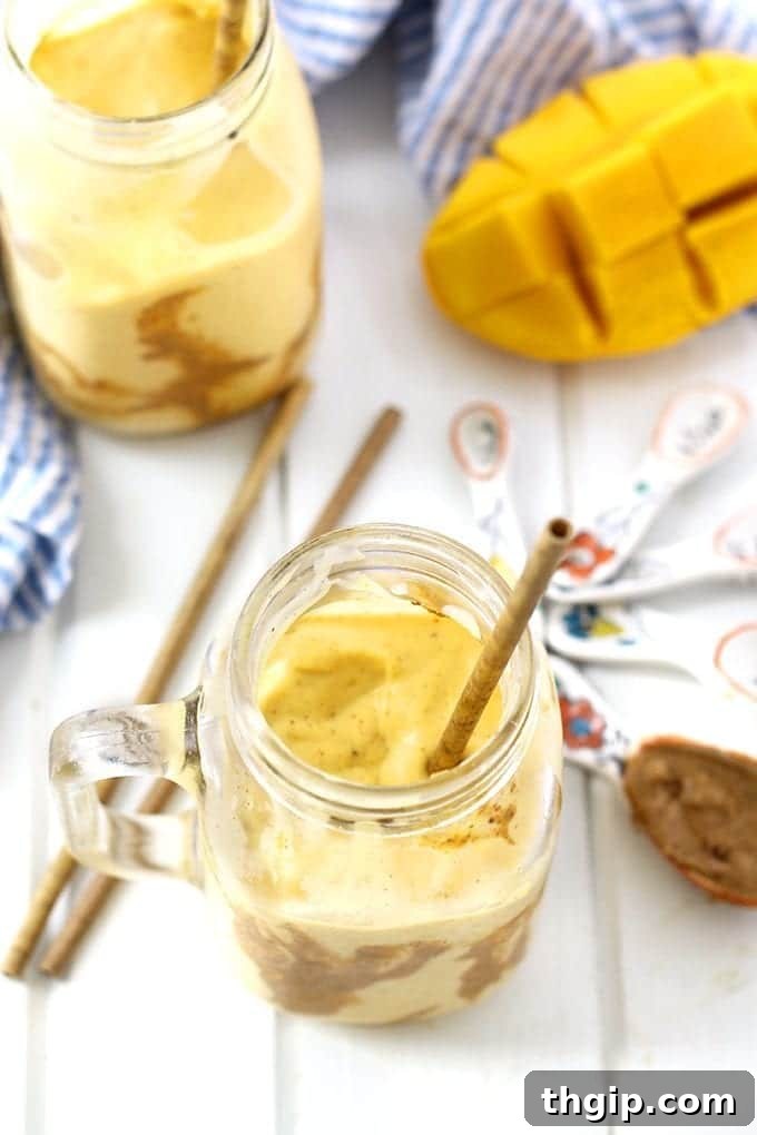 Tropical Mango Almond Bliss 4 Close-up of a creamy Mango Almond Butter Smoothie in a glass, with a spoon for eating thick smoothies.