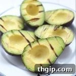 Grilled avocado halves with seasoning, showcasing a perfect char for a delicious meal.