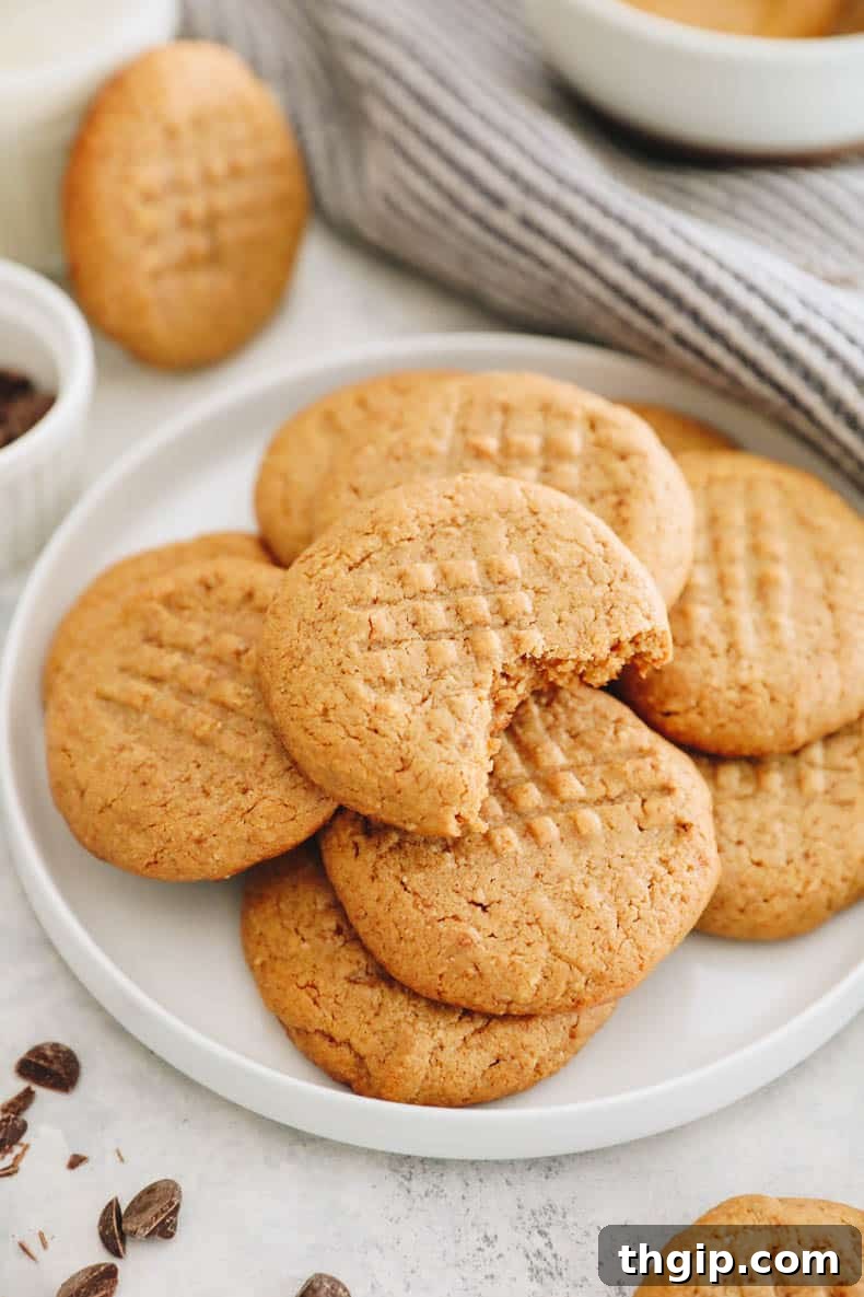 Wholesome Peanut Butter Treats 2 Stacked healthy 3-ingredient peanut butter cookies on a white plate, showcasing their golden brown edges and chewy interior.