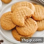 healthy peanut butter cookies on a plate with a bite taken out of the top cookie.
