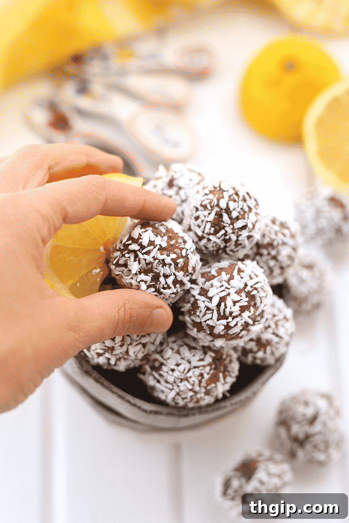 A close-up shot of a single Lemon Coconut Energy Ball, highlighting its texture and the coconut coating, suggesting its deliciousness and appeal.