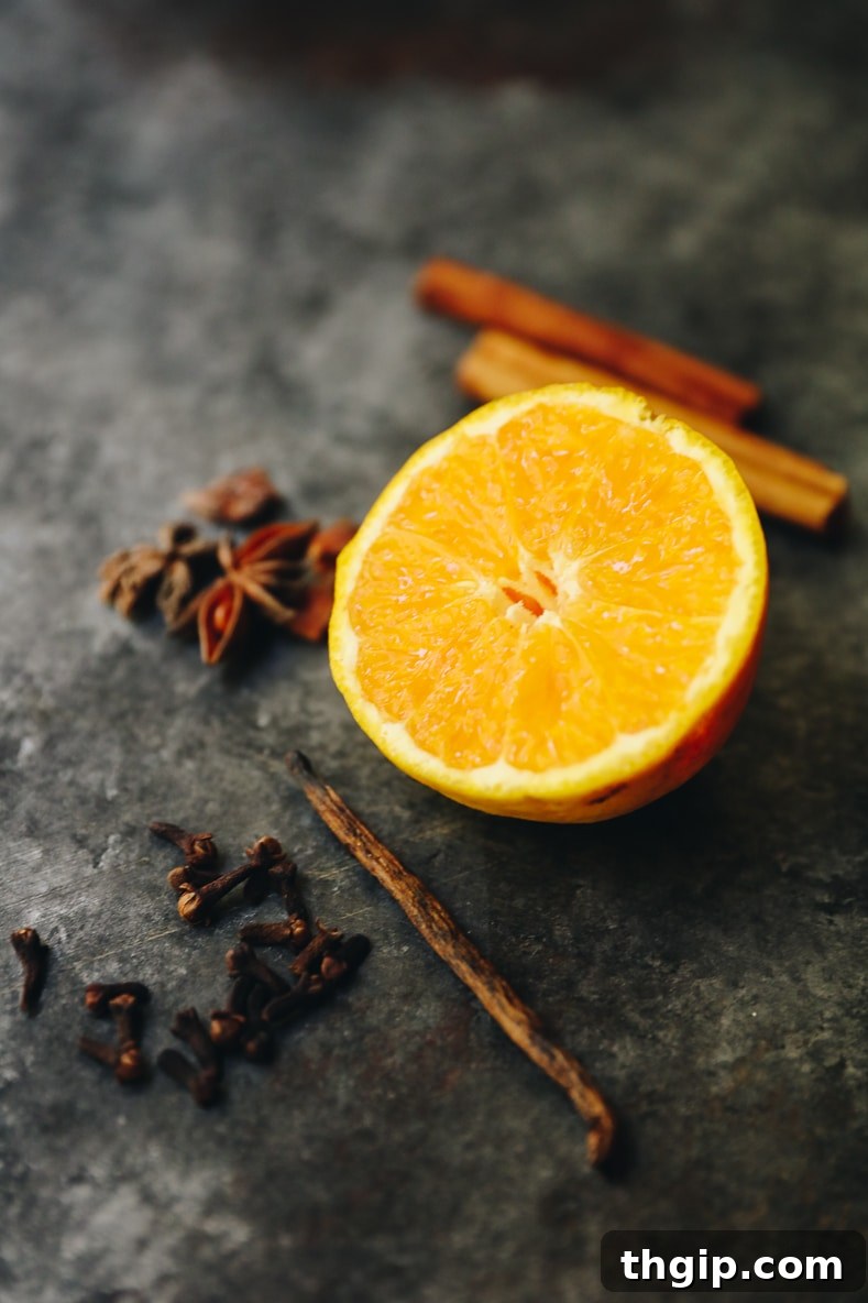 The Scent of Fall: Easy Simmer Pot Spices 3 Ingredients for fall simmering spices laid out on a wooden surface: vibrant orange peels, aromatic cinnamon sticks, a delicate vanilla bean, and pungent whole cloves