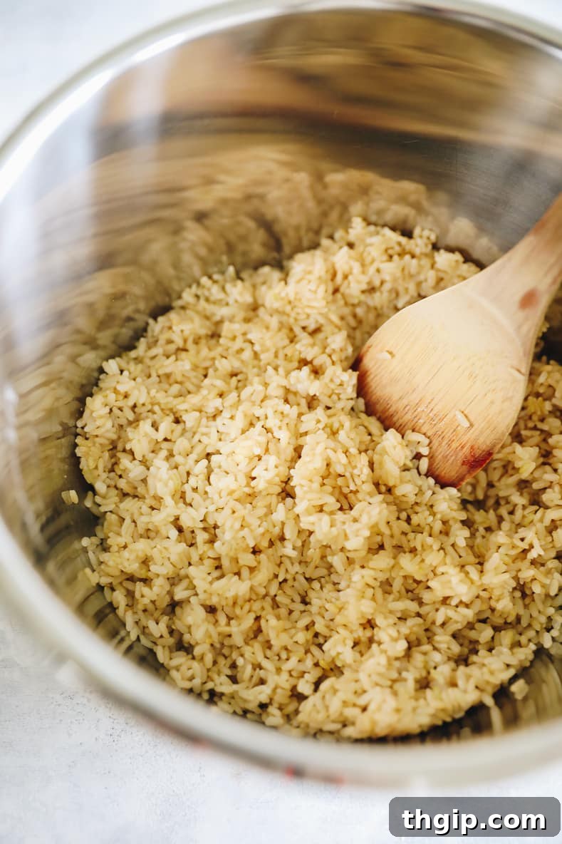 Brown rice cooking in a large pot, being stirred with a wooden spoon for perfect texture.