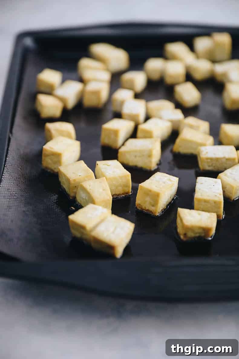 Crispy roasted tofu cubes on a baking sheet, ready for a healthy Buddha Bowl.
