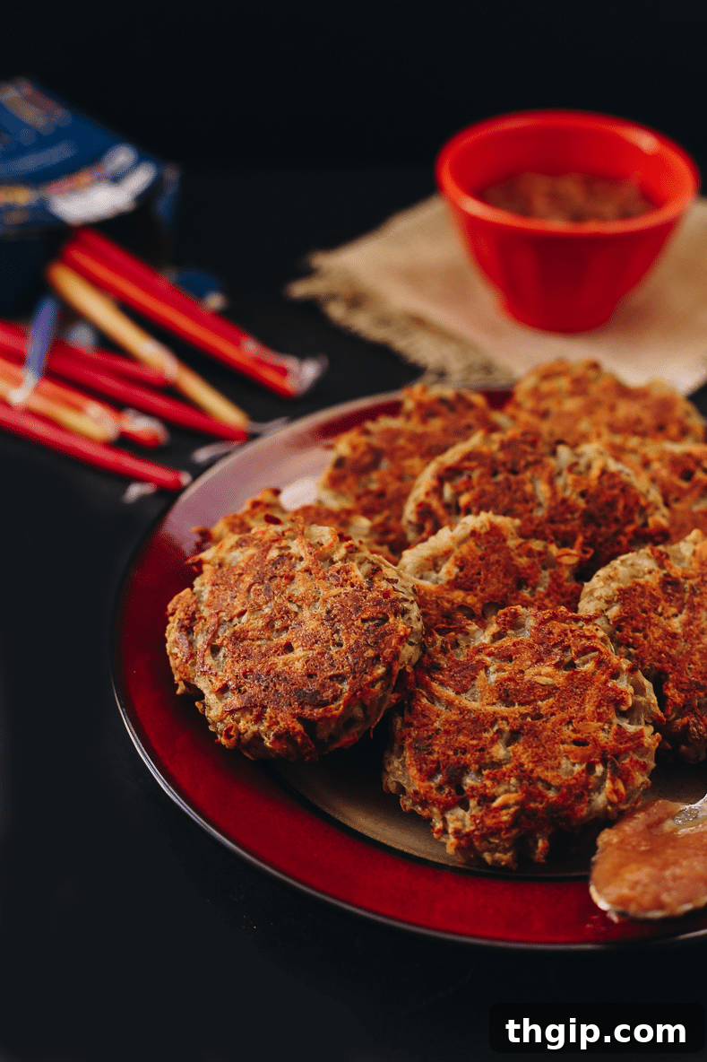 Crispy Baked Latkes Naturally Gluten Free and Vegan 5 A close-up of several golden brown healthy baked latkes artfully arranged on a serving plate.