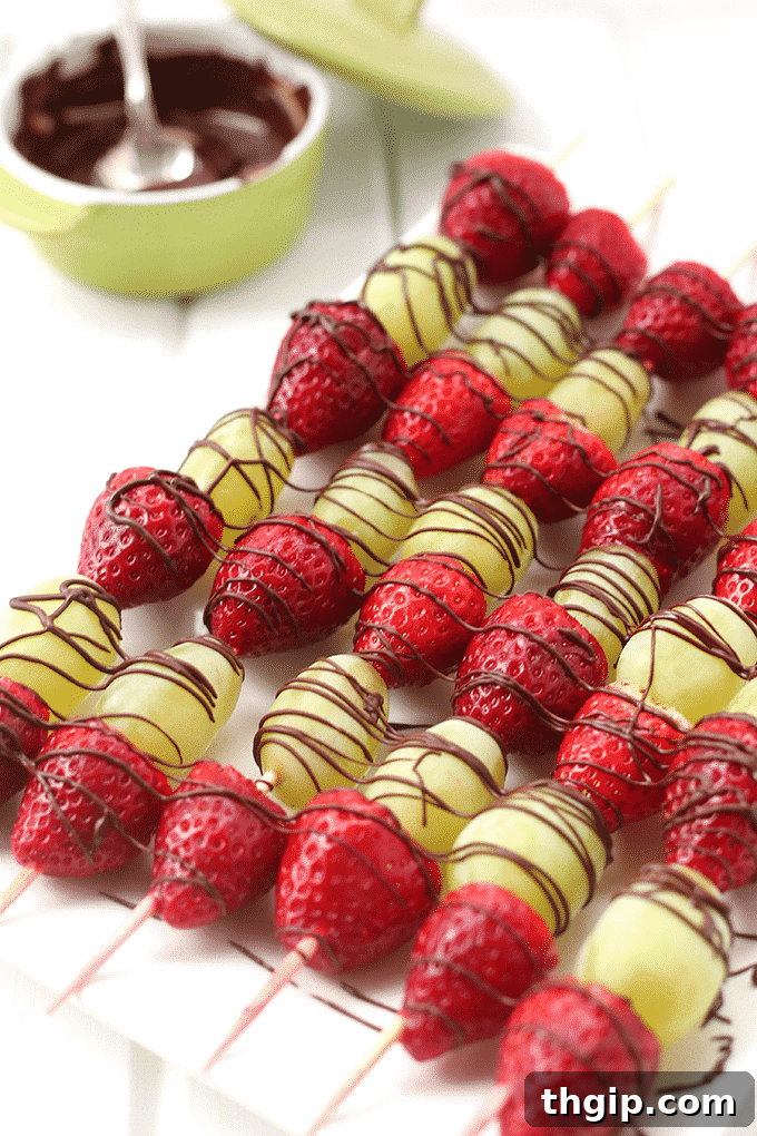 Vibrant chocolate-drizzled fruit skewers arranged beautifully on a platter, showcasing fresh strawberries and green grapes