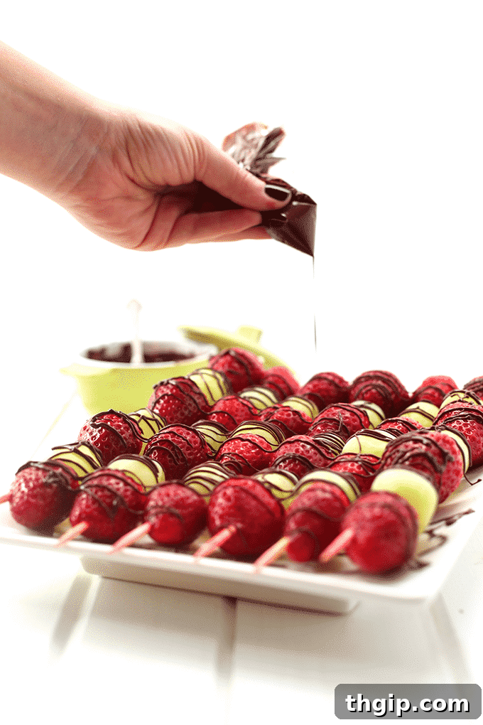 A beautifully presented platter of chocolate-drizzled strawberry and green grape skewers, ready for a party