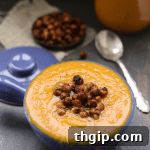 Creamy butternut squash soup in a bowl with roasted chickpeas on top.