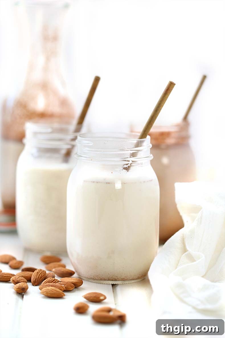 Create Your Own Creamy Almond Milk 2 A glass bottle of freshly made almond milk with a bowl of almonds in the background.