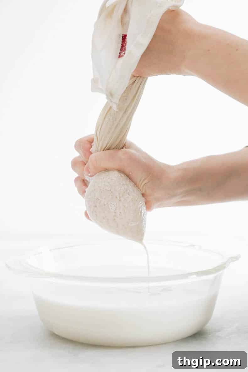 Create Your Own Creamy Almond Milk 5 Squeezing freshly blended almond milk through a nut milk bag into a large glass bowl.